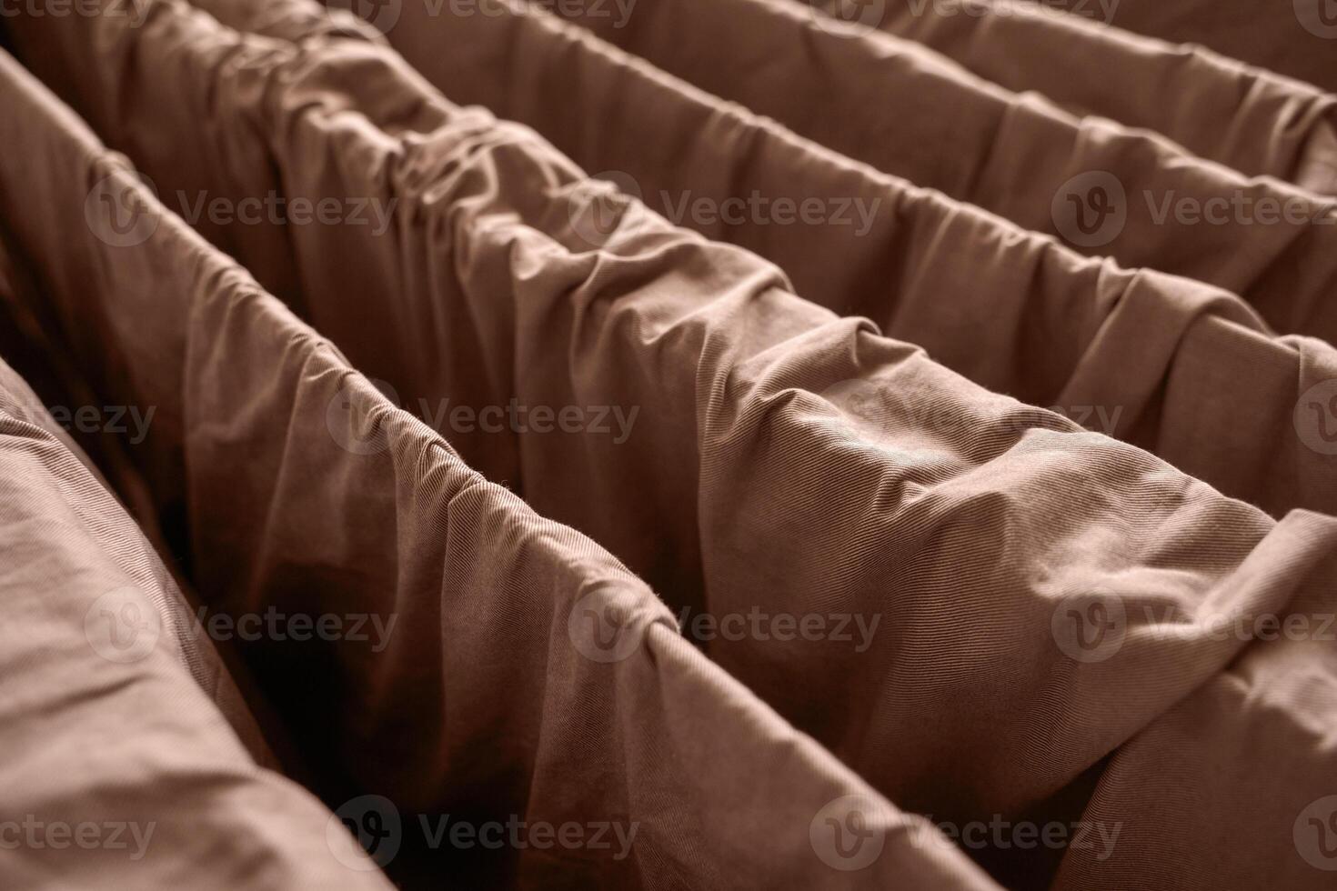 Close up of brown fabric with gathered texture and parallel folds creating a cozy and warm textile pattern. photo