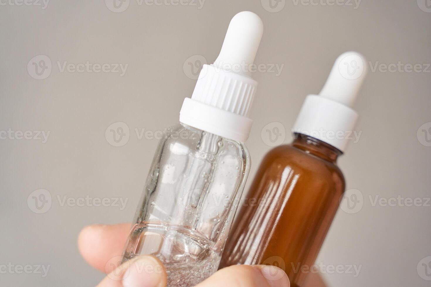 Close up of two dropper bottles with clear and brown liquid for skincare or essential oils. photo