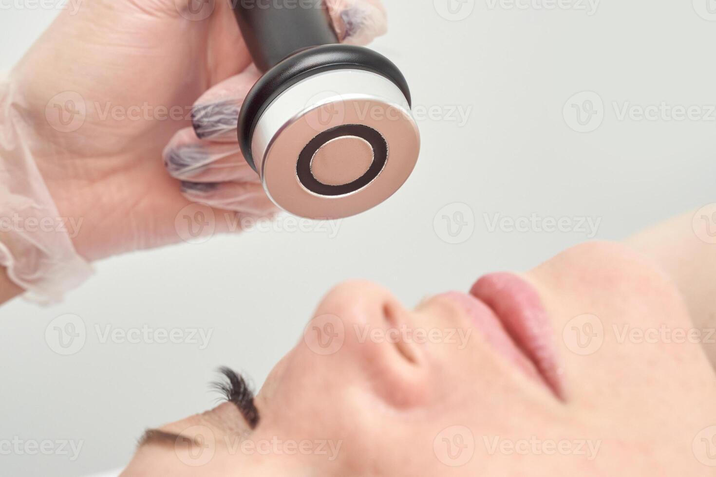 Caucasian female receiving facial treatment with rf device for skin rejuvenation in beauty clinic. photo