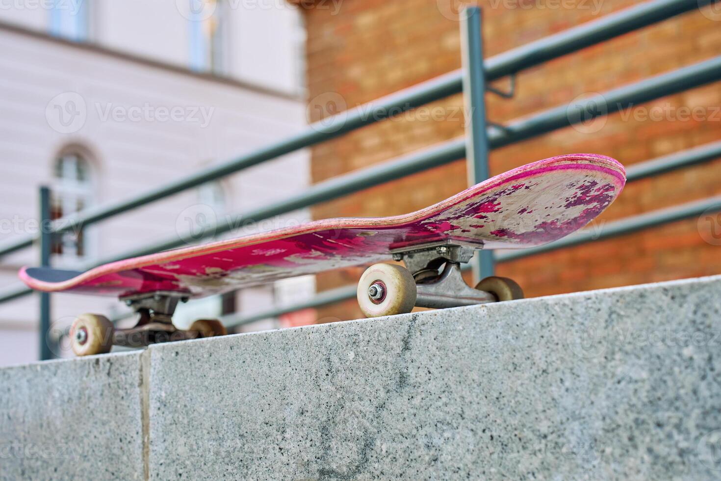 Used pink skateboard against stone wall in urban setting photo