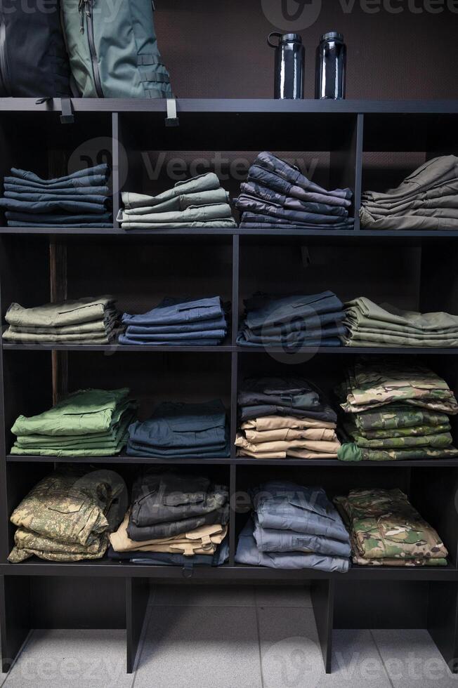 Folded Tactical Clothing and Military Uniforms on Shelves photo