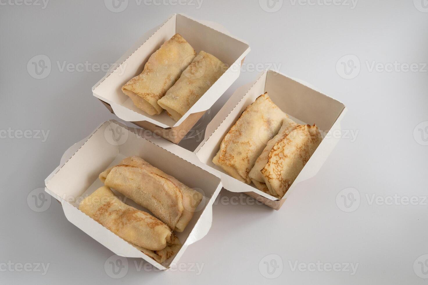 Three takeout boxes filled with neatly folded crepes, photo