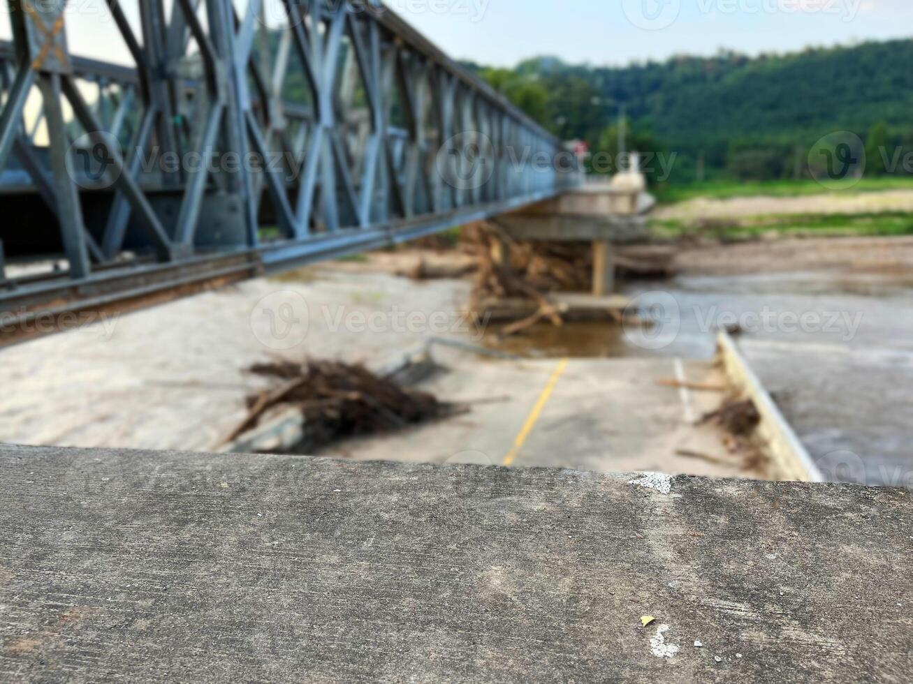 Steel bridge structure over a partially damaged or flooded river with debris accumulated below. A scene depicting infrastructure and natural forces, ideal for themes of construction, flood aftermath photo