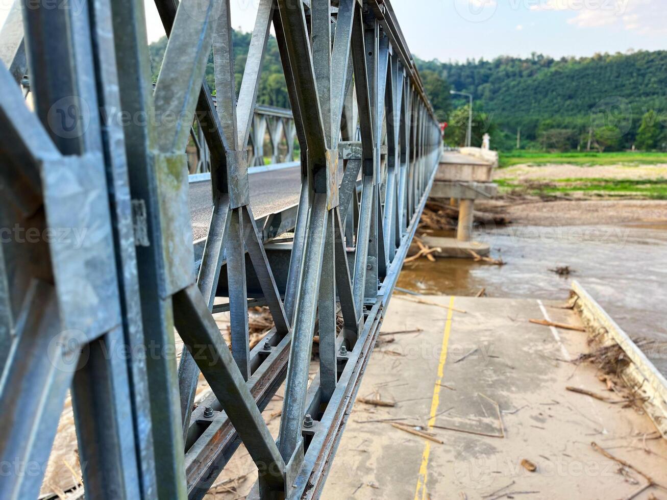 Steel bridge structure over a partially damaged or flooded river with debris accumulated below. A scene depicting infrastructure and natural forces, ideal for themes of construction, flood aftermath photo