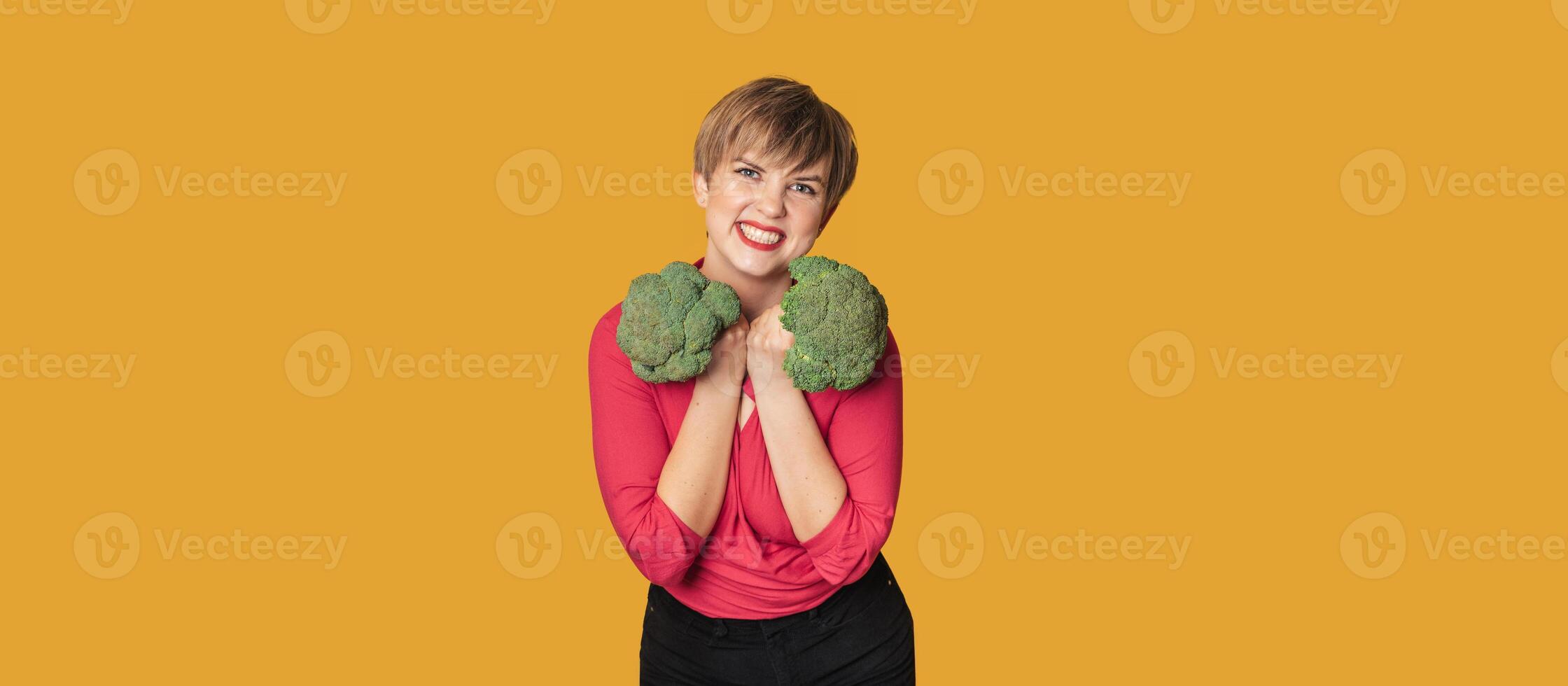 A studio shot of a young woman holding fresh broccoli in her hands. The concept of healthy food. A place for your text. Panoramic banner. photo