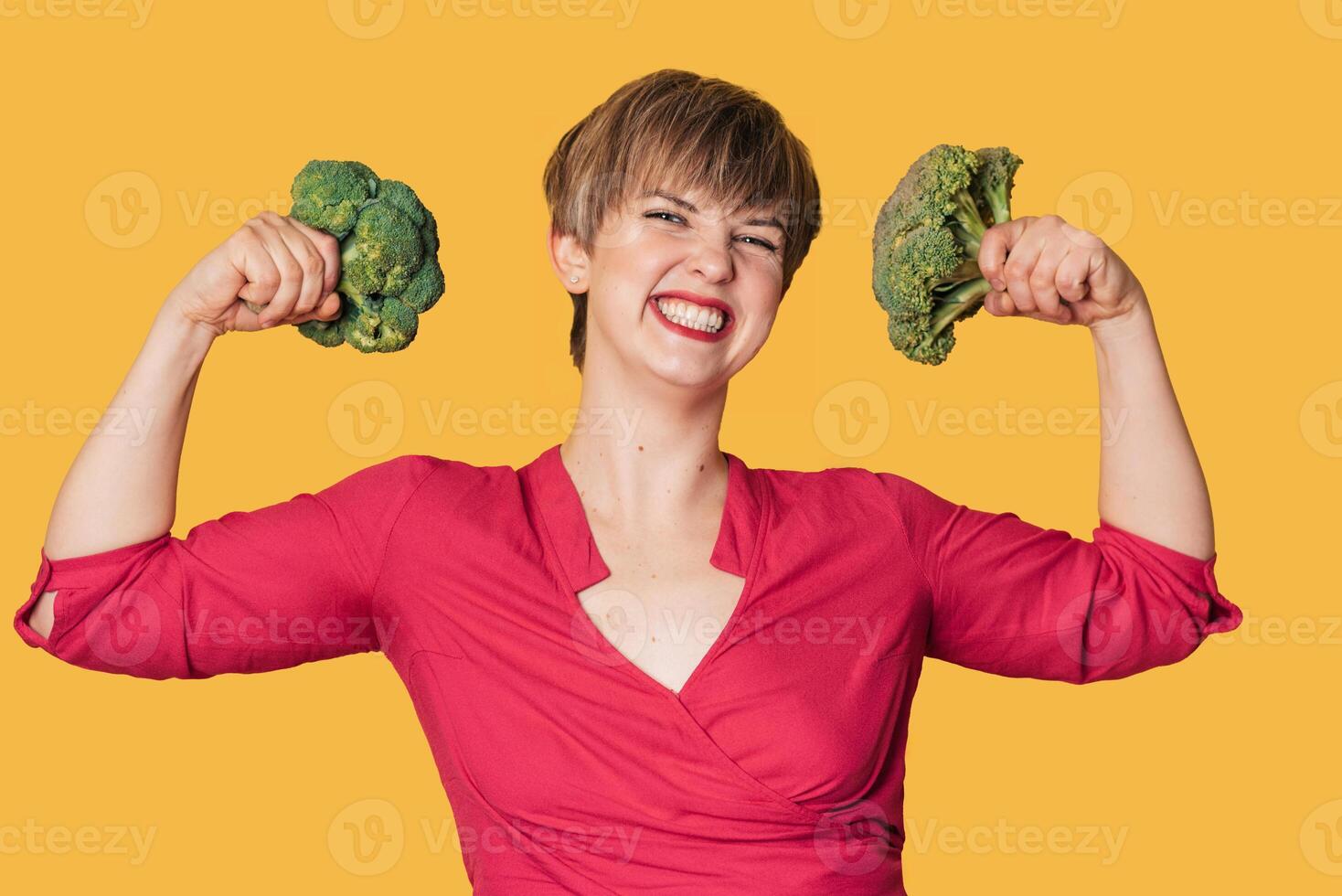 Broccoli in the hand of a slender smiling woman on a yellow background. healthy lifestyle. photo