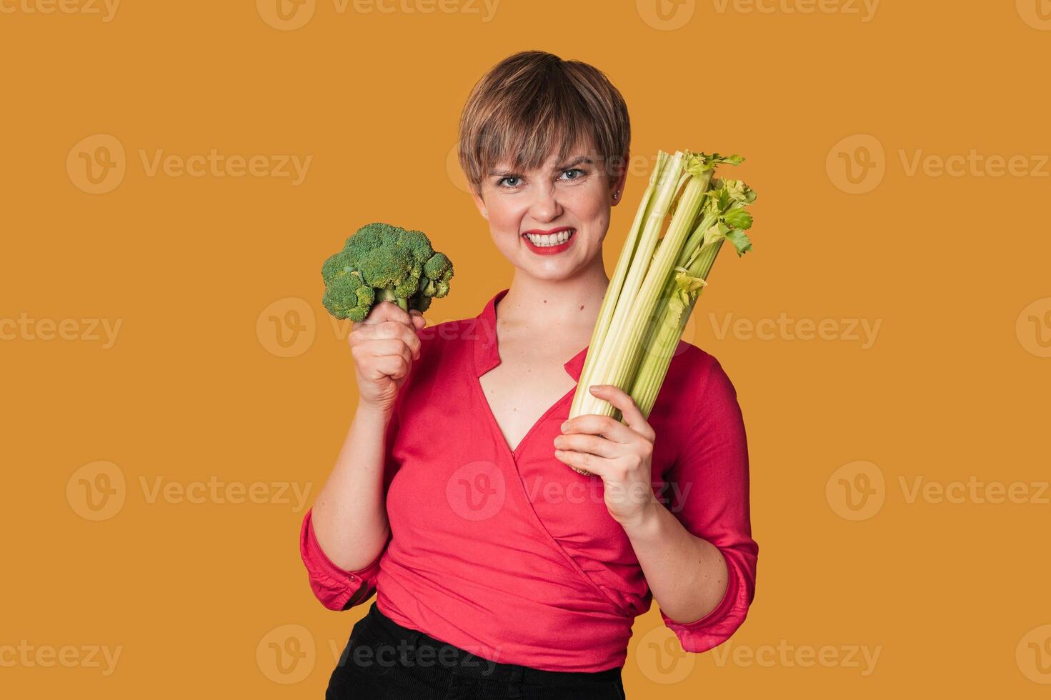 Smiling slender Caucasian girl with green vegetables in her hands, broccoli and celery, Organic vegetables. photo