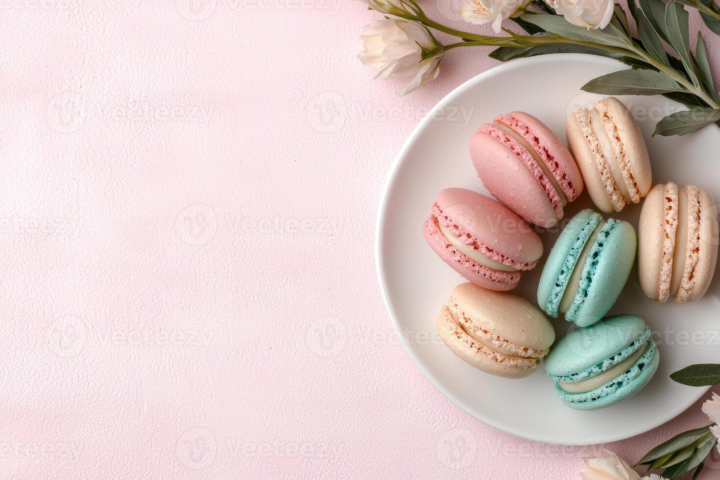 Pastel macarons and flowers on pink background photo
