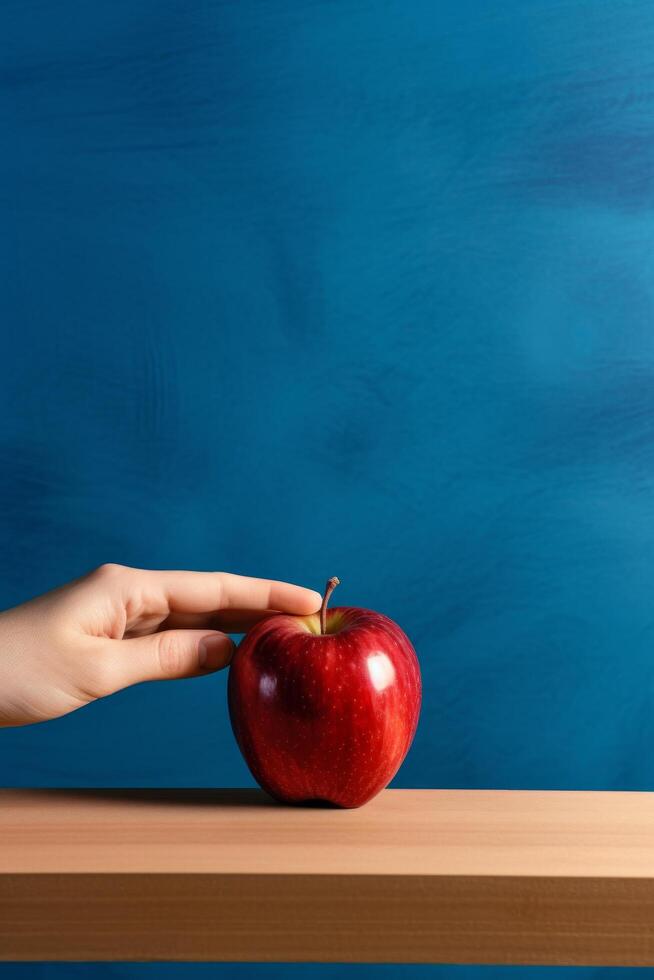 Red apple on wooden table against blue background photo