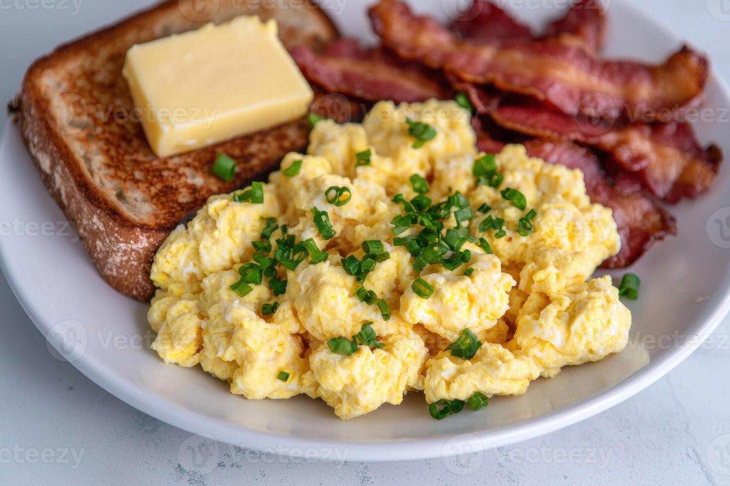 Delicious breakfast plate with scrambled eggs, bacon, toast, and butter photo