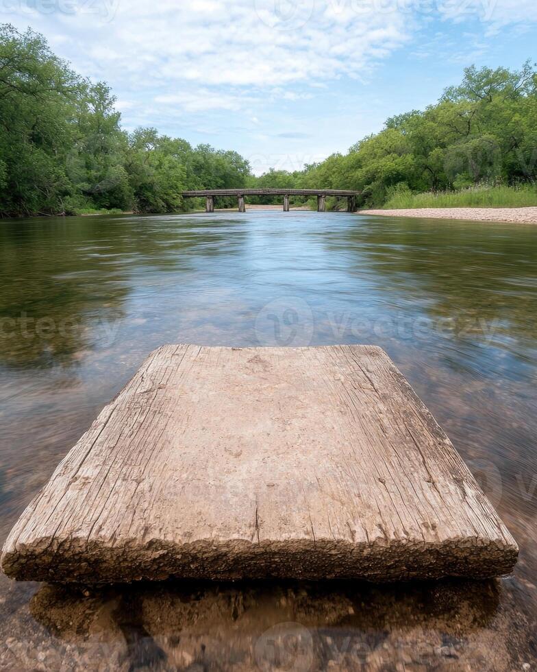Rustic wooden platform in shallow river with old bridge in background photo