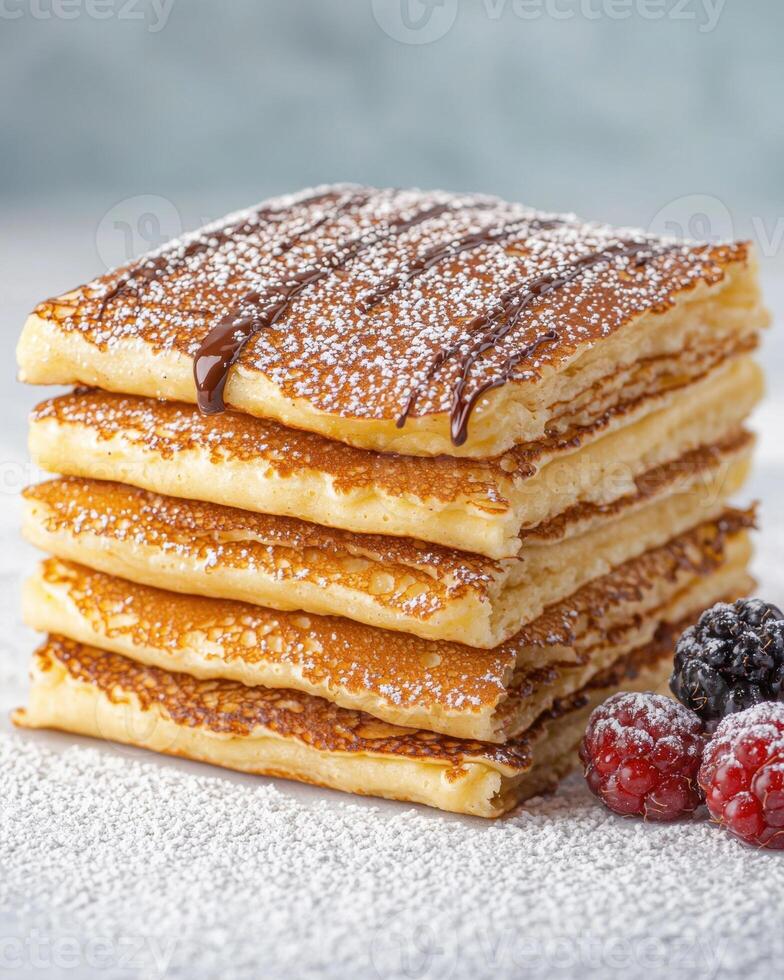 Delicious fluffy pancakes stack with chocolate syrup and powdered sugar, served with fresh berries photo