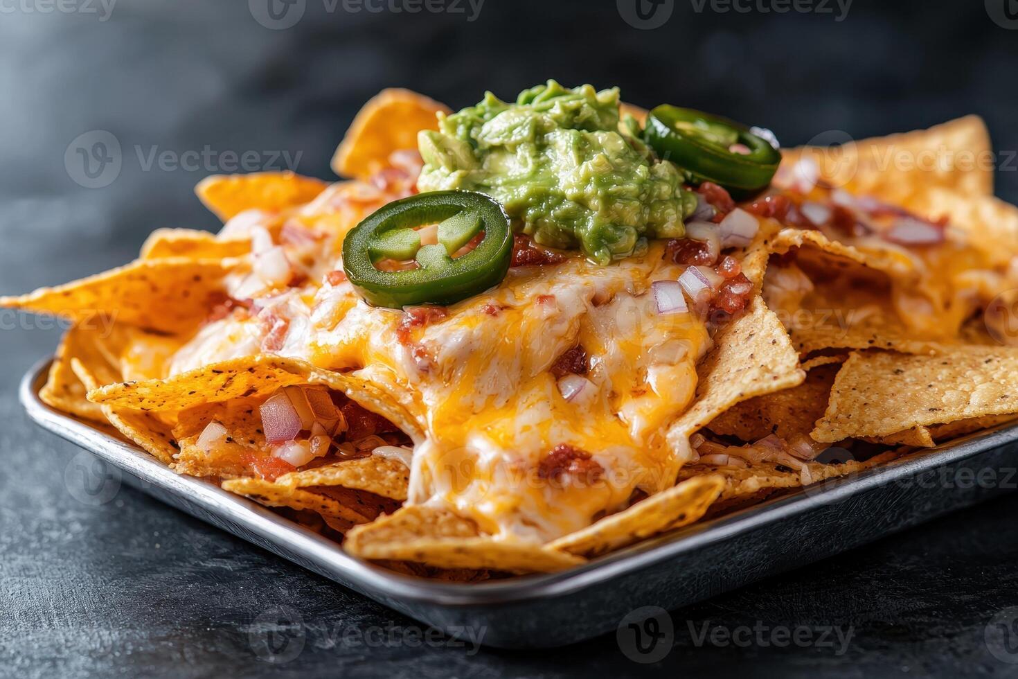 Loaded nachos with melted cheese, guacamole, jalapenos, and onions photo
