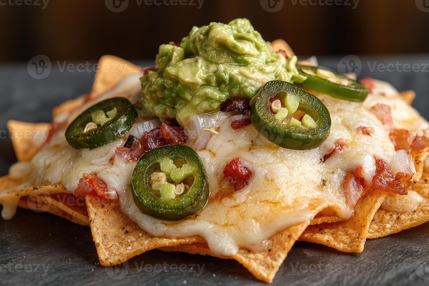 Delicious nachos with guacamole, jalapenos, bacon, and cheese photo