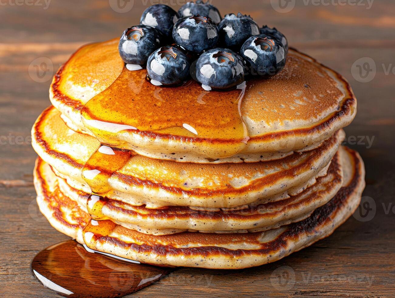 Stack of fluffy pancakes topped with fresh blueberries and maple syrup photo