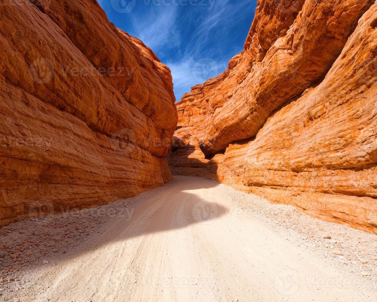 Sandy road through a red rock canyon under a blue sky photo