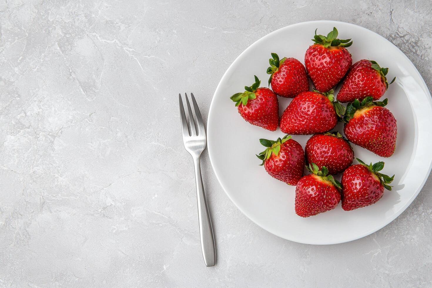 Fresh strawberries on a white plate with a fork, ready to eat photo