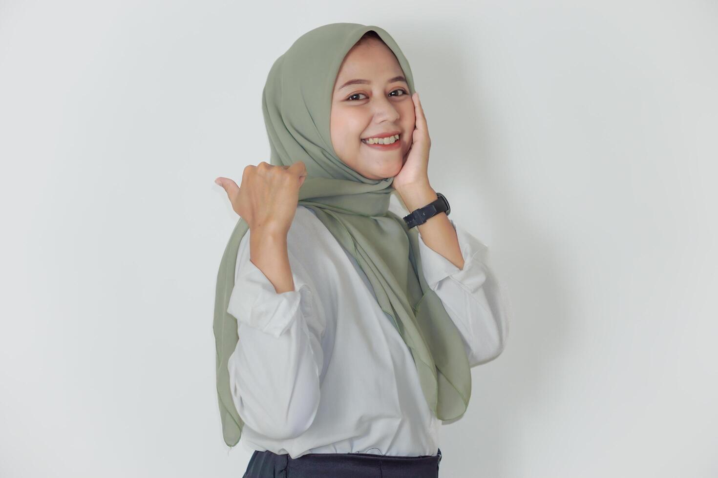 A young asian woman in a green hijab smiles confidently, showcasing positivity and charm. photo
