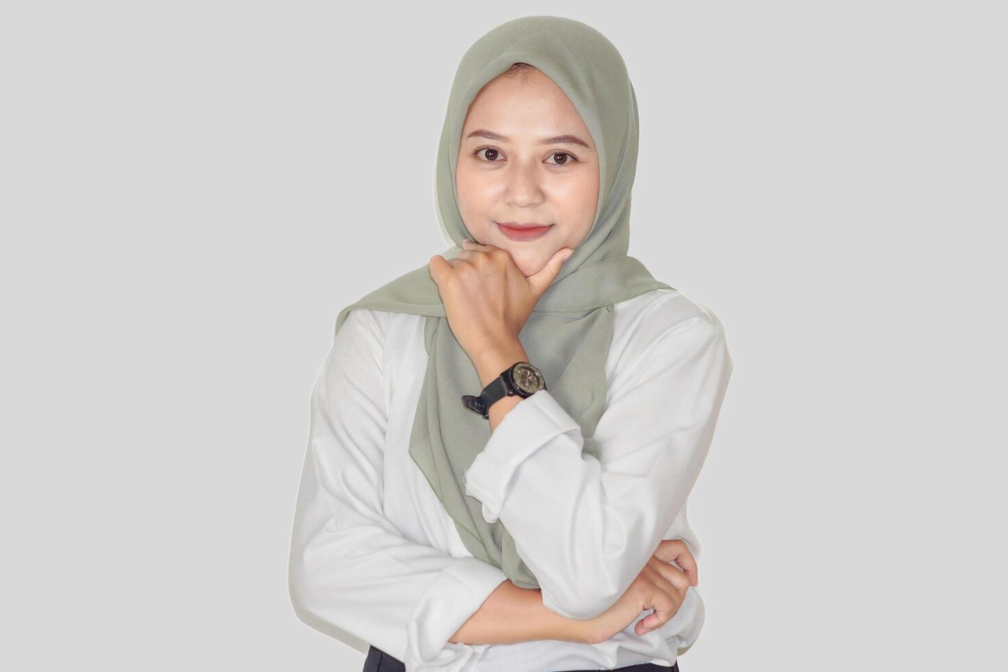 Confident asian woman in a green hijab poses thoughtfully, showcasing a professional demeanor. photo