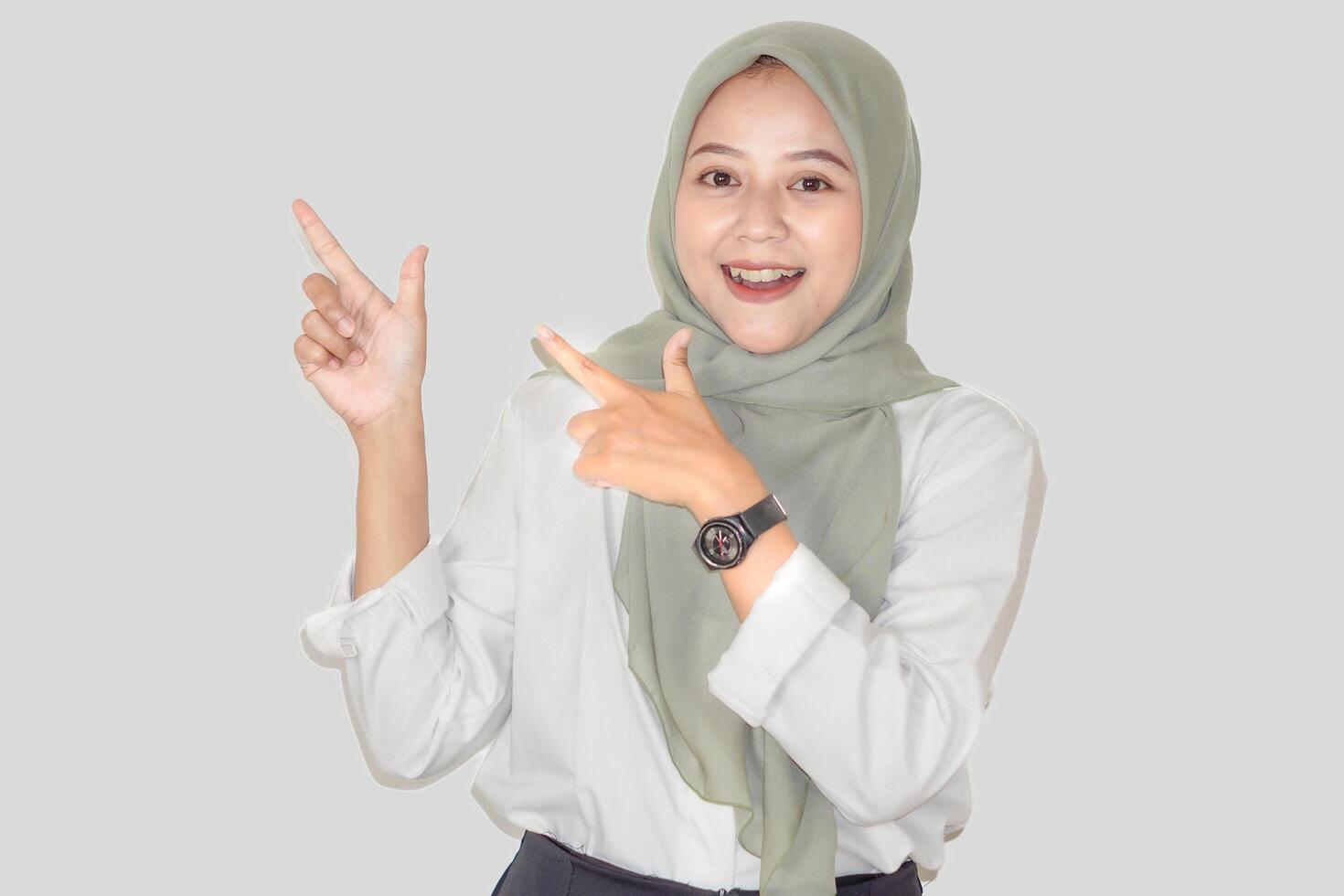A cheerful asisan woman in a green hijab happily gestures with her hands, expressing enthusiasm. photo
