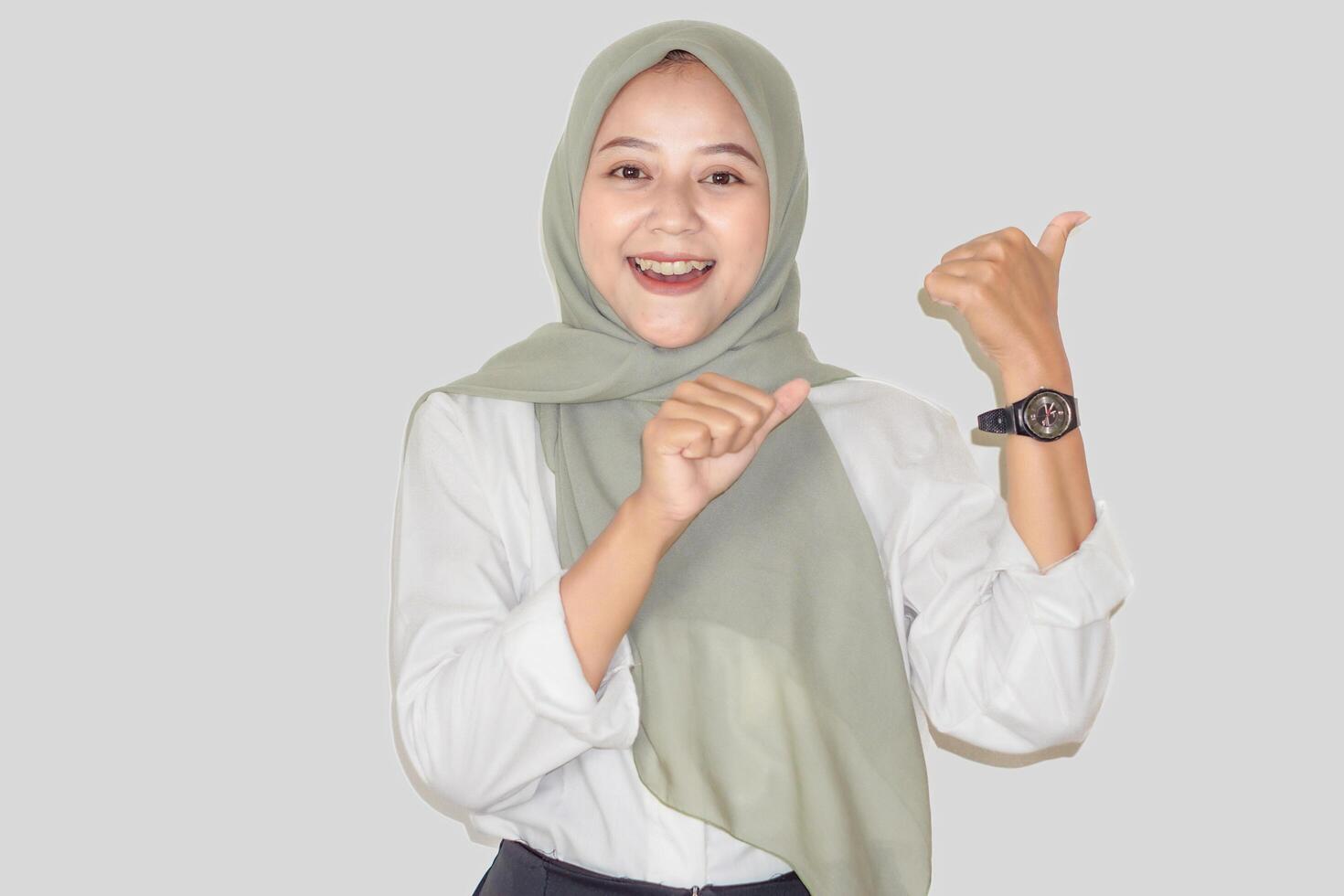 A cheerful woman in a green headscarf points to the back using her thumbs photo