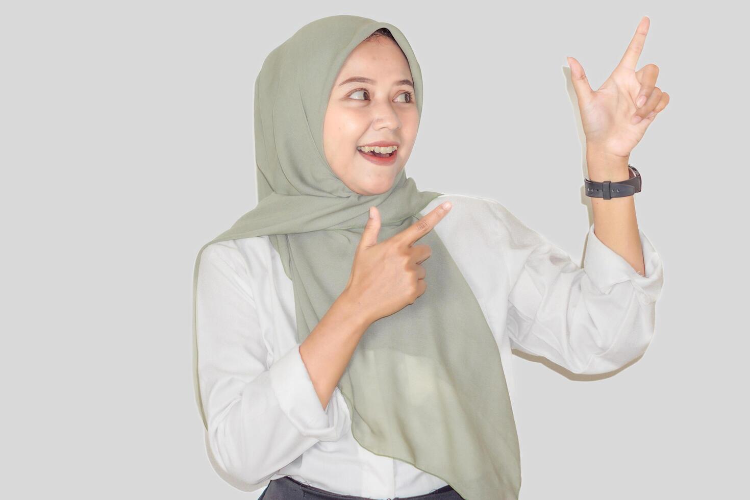 A cheerful asisan woman in a green hijab happily gestures with her hands, expressing enthusiasm. photo