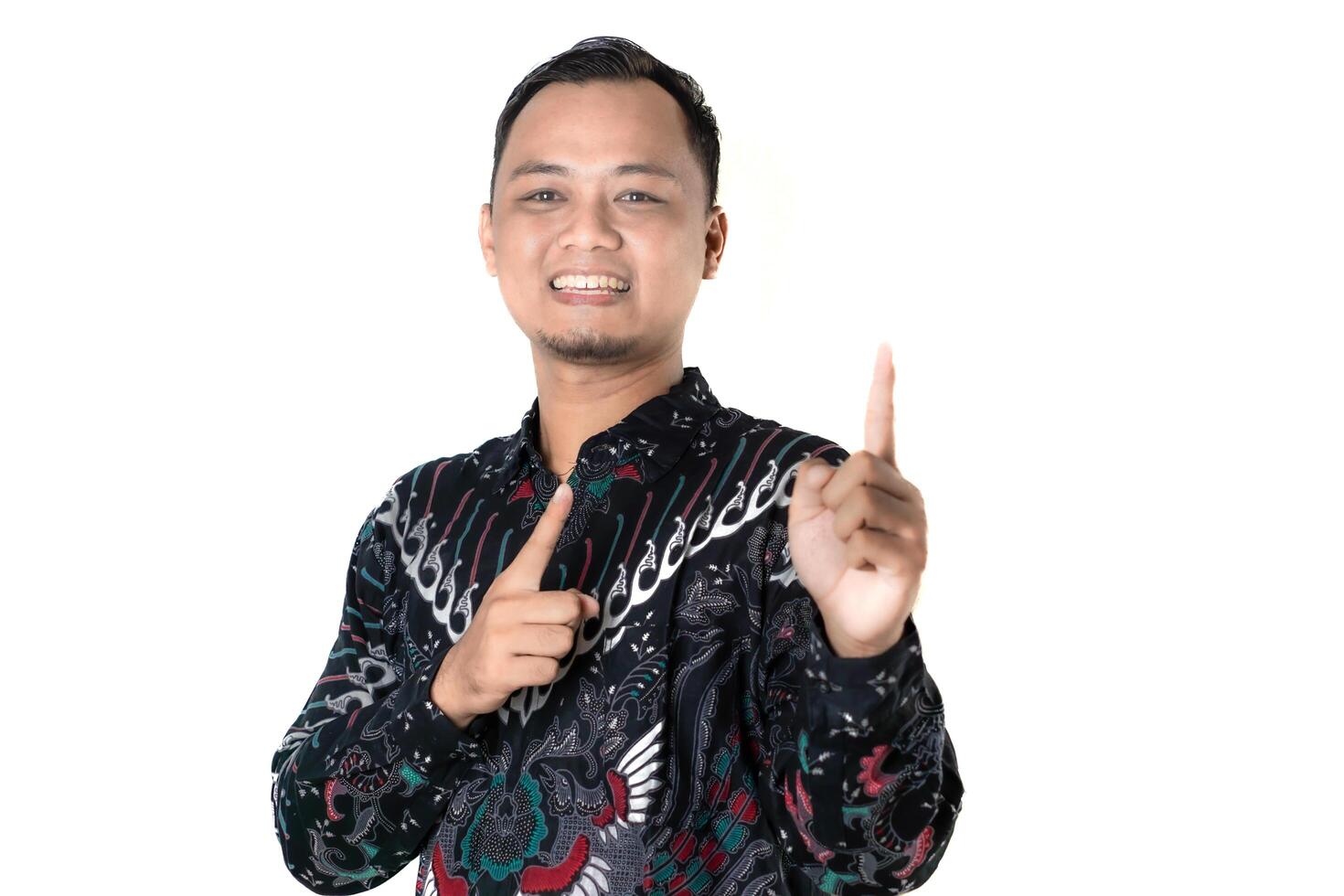 Portrait of a Man in a Batik Shirt Cheerfully Pointing Up photo