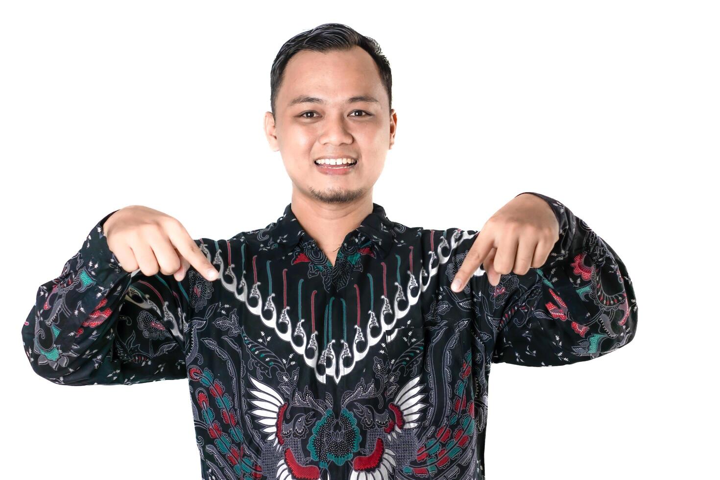 Enthusiastic Man in Batik Shirt Pointing Down with Excitement and a Smile photo