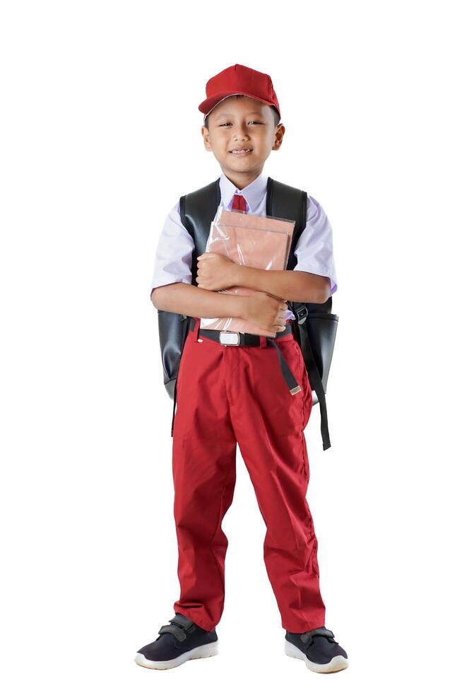A Indonesian kid student in red and white uniform with a backpack, holding books and looking confident. photo