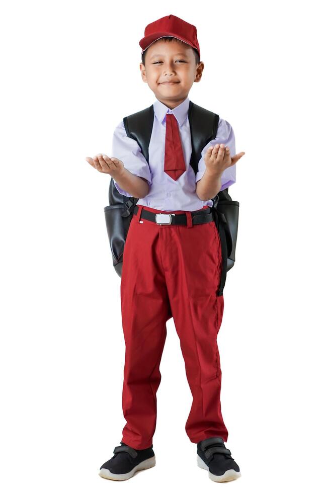 A Indonesian young student in a red and white uniform, smiling with arms open, wearing a backpack and hat. photo