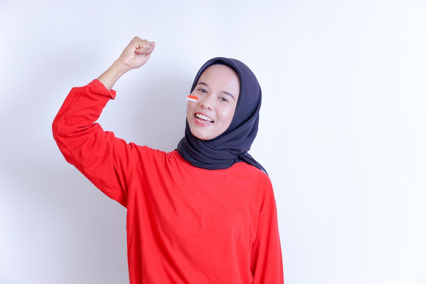 A young Indonesian woman wearing a headscarf is depicted with a radiant smile, clenching her hand to celebrate Indonesia's independence day on August 17. photo