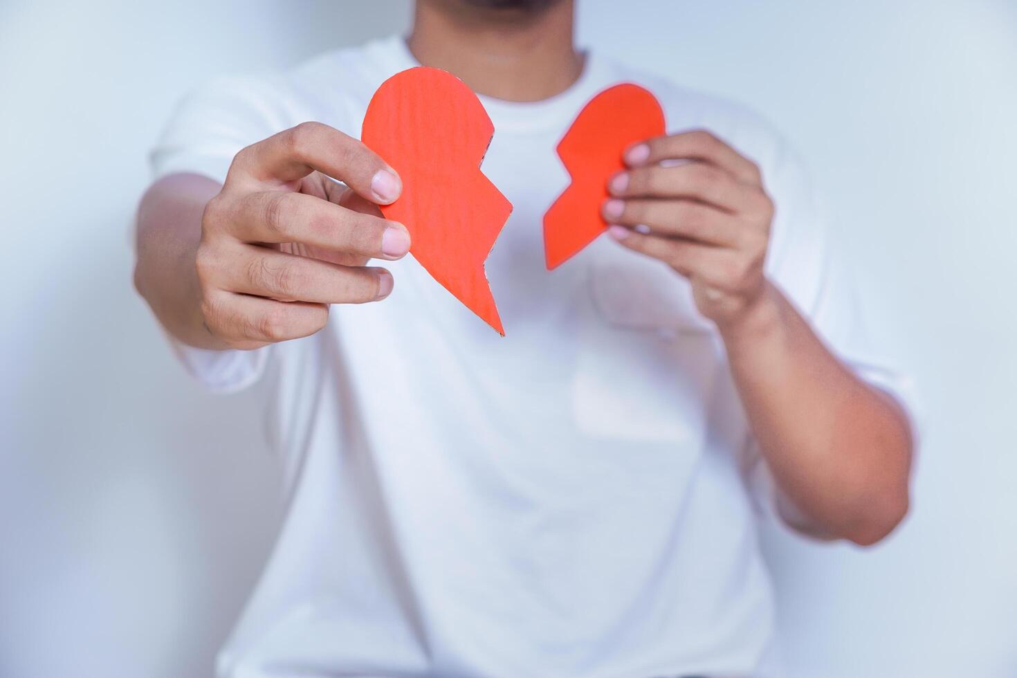 A person holding a broken heart symbol, representing heartbreak or emotional distress. photo