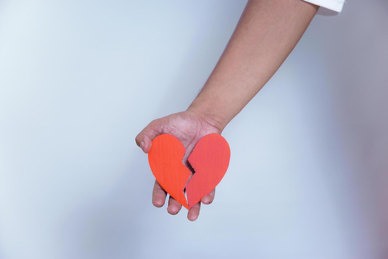 A person holding a broken heart symbol, representing heartbreak or emotional distress. photo