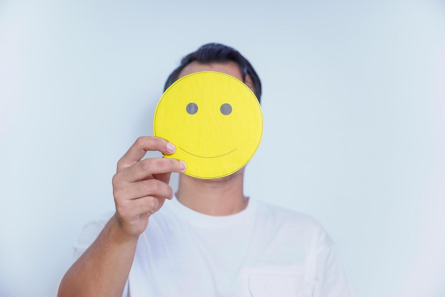 A person holding a cheerful yellow smiley face symbolizes joy and positivity in a bright setting. world mental health day concept photo