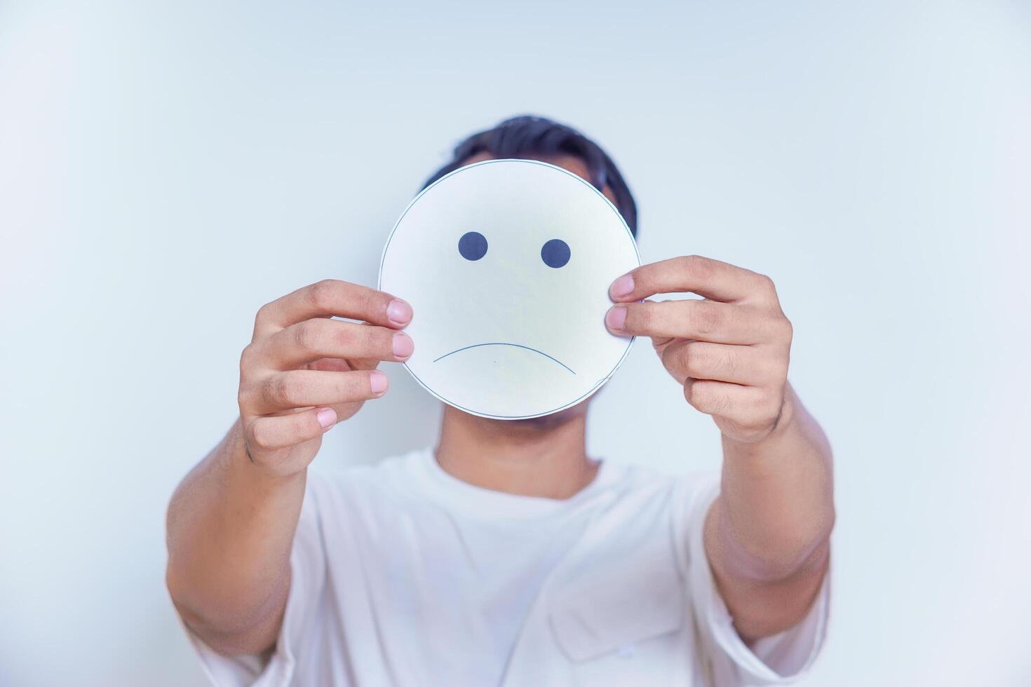 A person holds a sad face symbol, reflecting emotions and the complexity of feelings we often hide. world mental health day concept photo