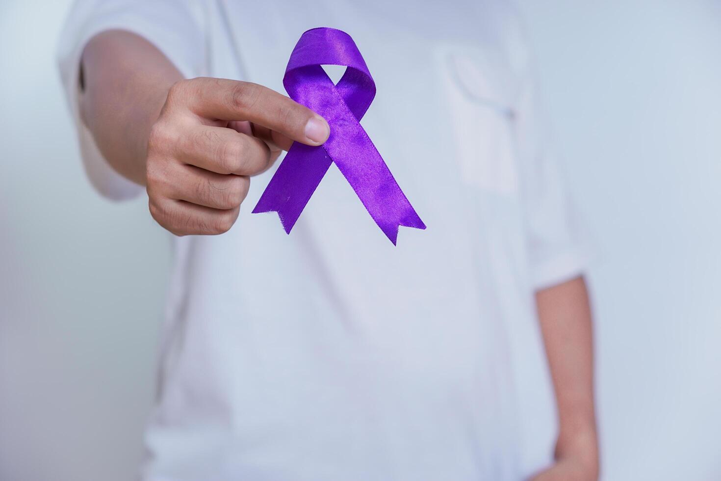 A person holding a purple ribbon, symbolizing awareness and support for various causes, including cancer. Healthcare and World cancer day concept photo