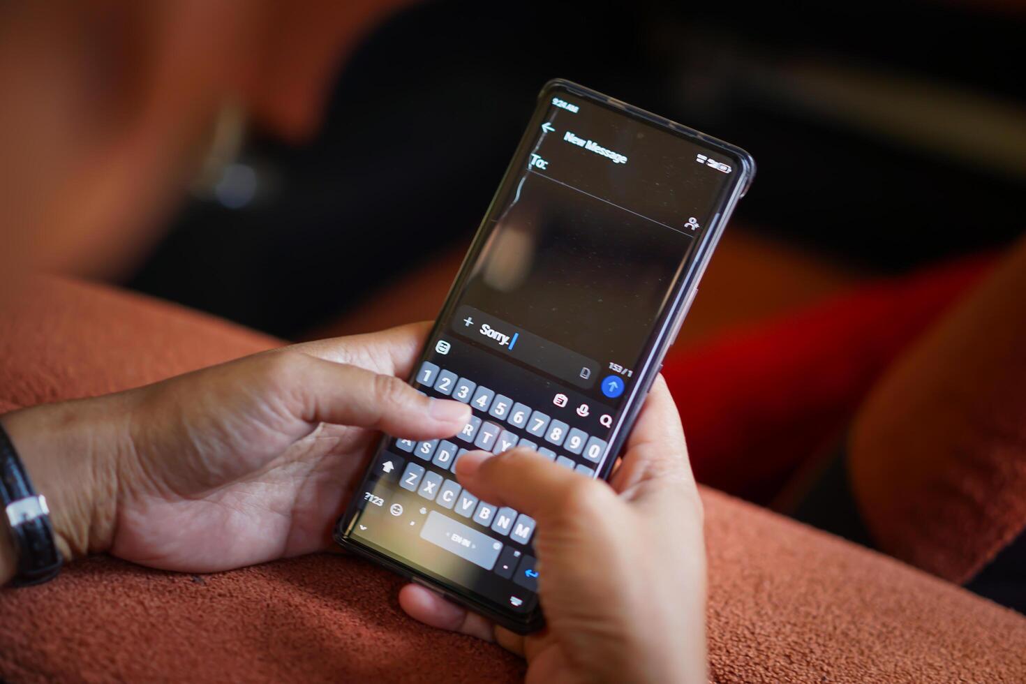 A person typing a sorry message on a smartphone, showcasing modern communication on a cozy couch. photo