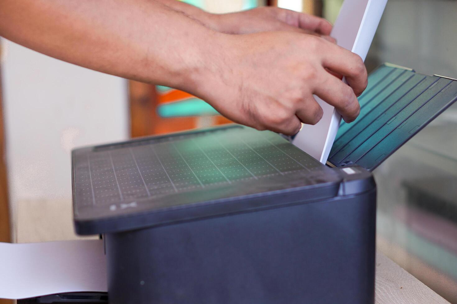 A person feeds blank paper into the printer photo