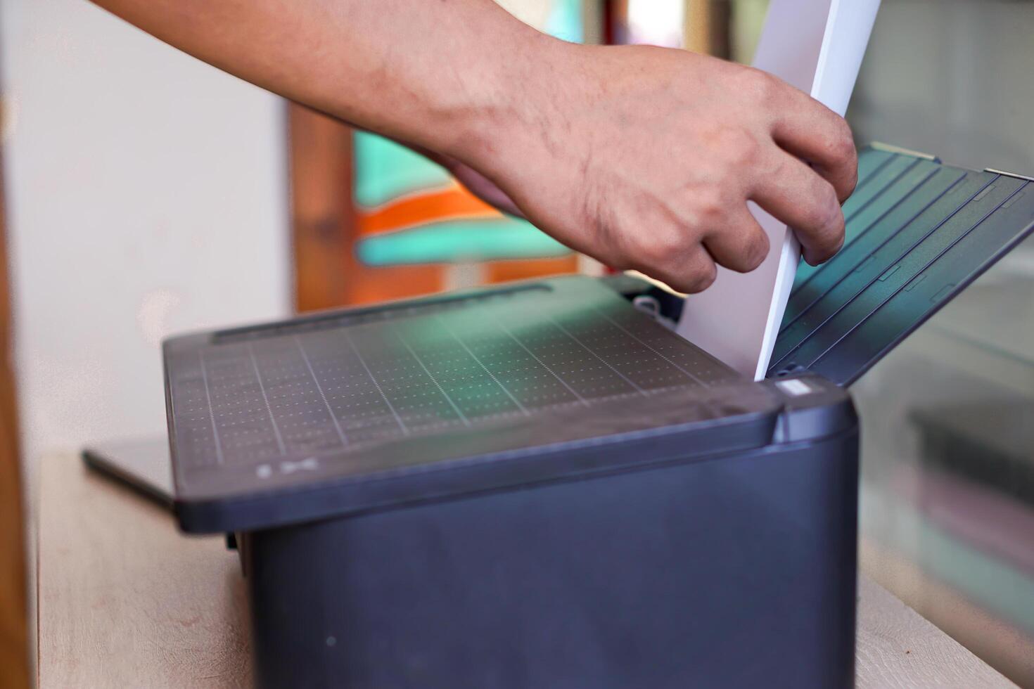A person feeds blank paper into the printer photo