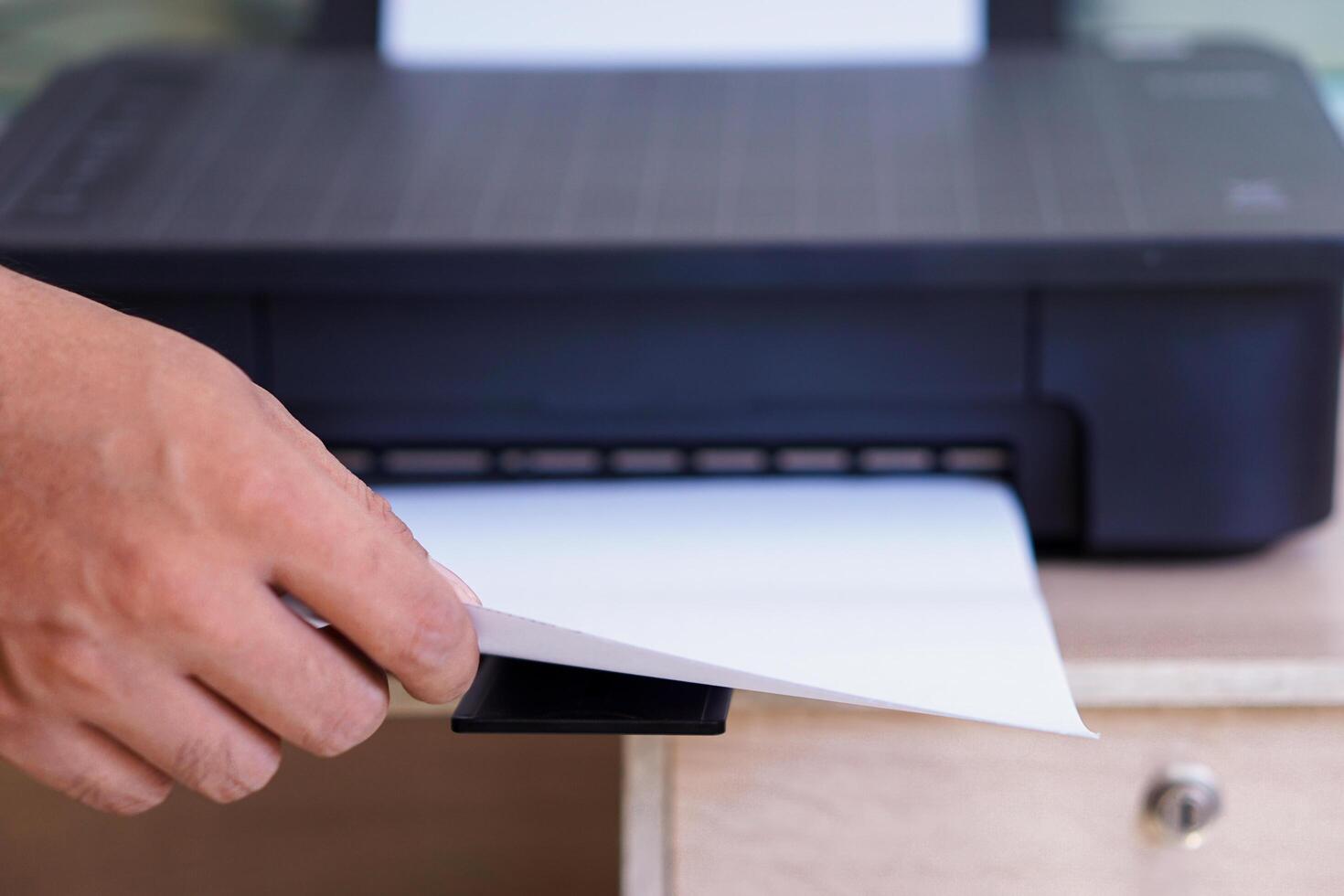A person taking printed paper from a printer photo