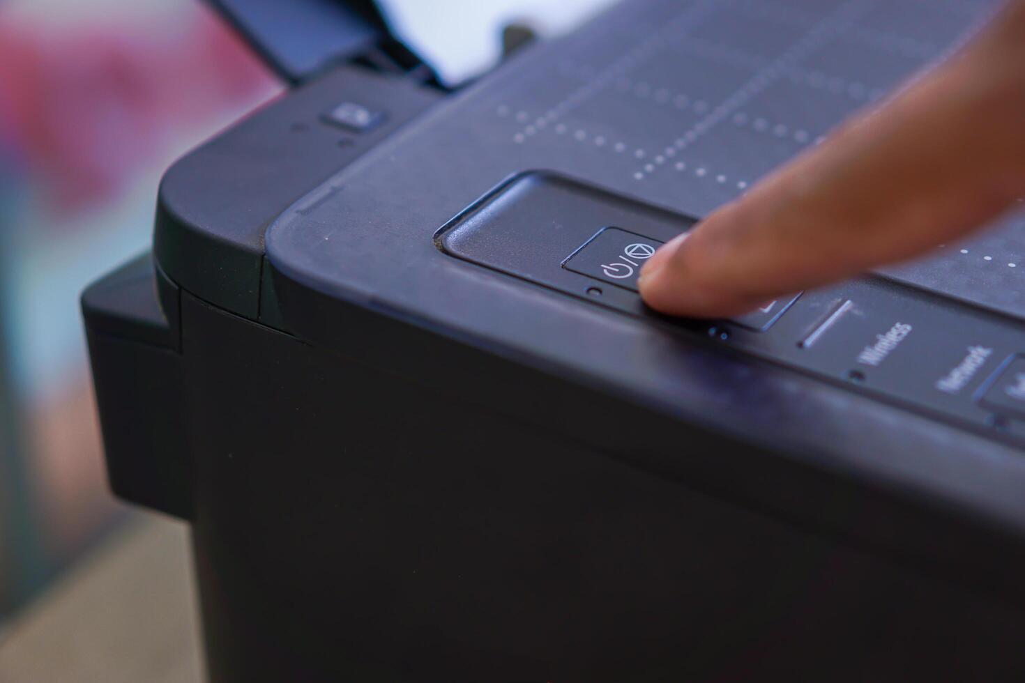 Finger pressing the printer power button photo