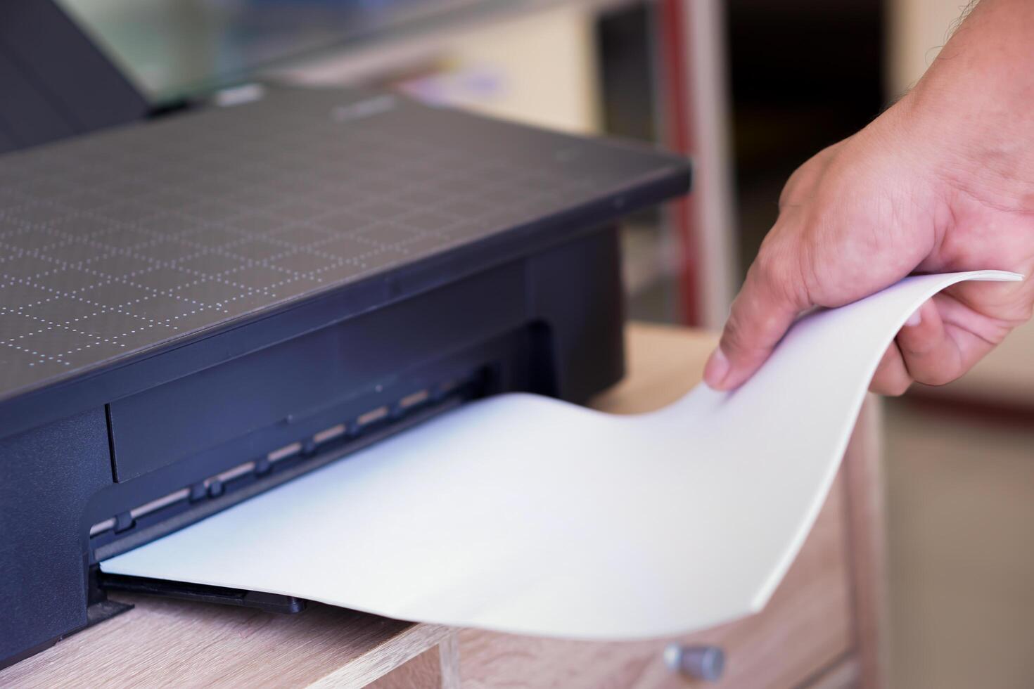 A person taking printed paper from a printer photo