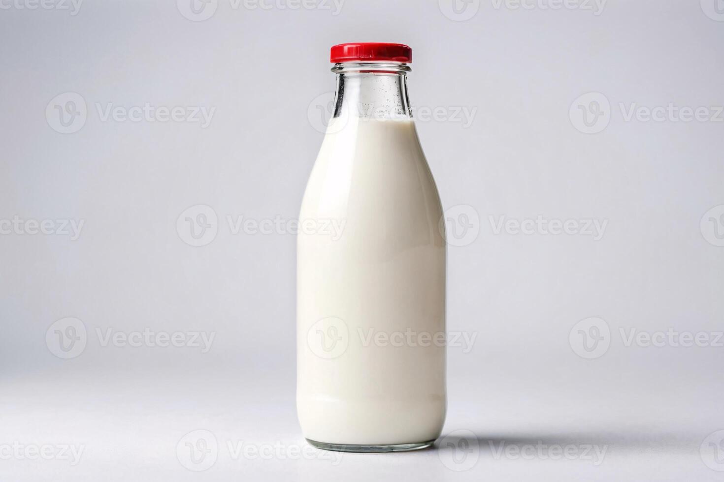 Glass bottle filled with milk with a red lid on a white background. photo