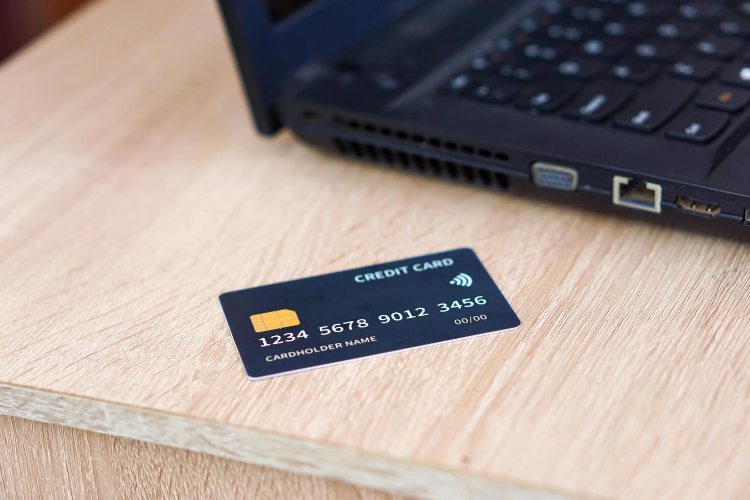 A credit card placed beside a laptop on a wooden table, showcasing modern payment methods. photo