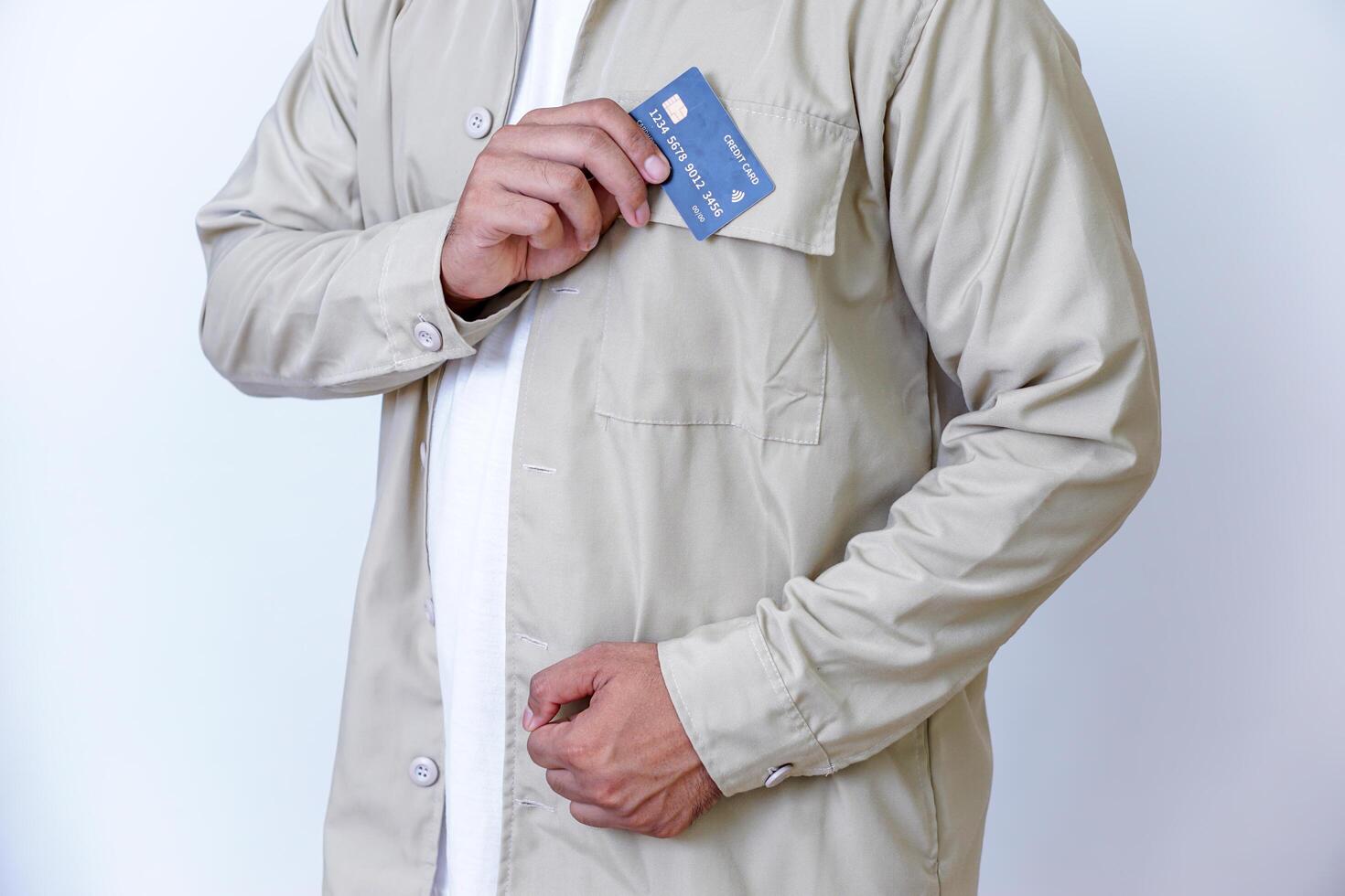 A young man in a beige jacket proudly displays his credit card photo