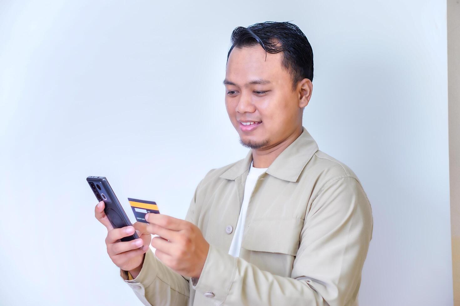 A cheerful man holding a smartphone and credit card, ready for a transaction. photo