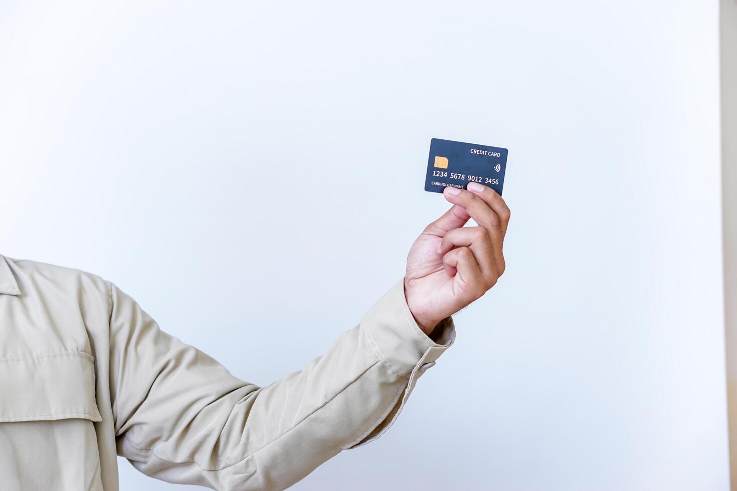 A hand holding a modern credit card with a microchip against a plain background. photo