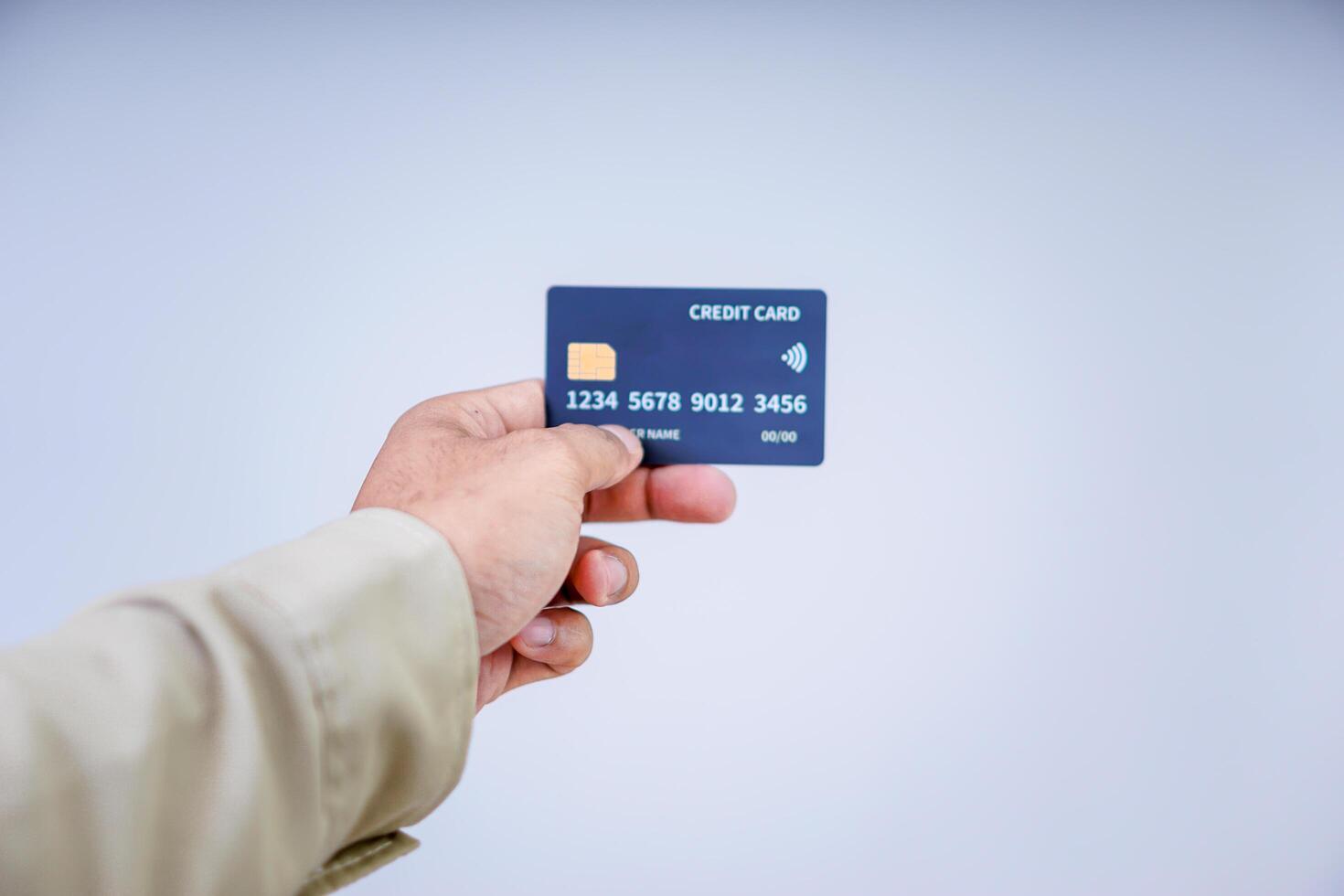 A hand holding a modern credit card with a microchip against a plain background. photo