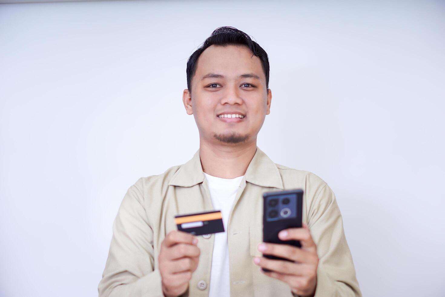 A cheerful man holding a smartphone and credit card, ready for a transaction. photo