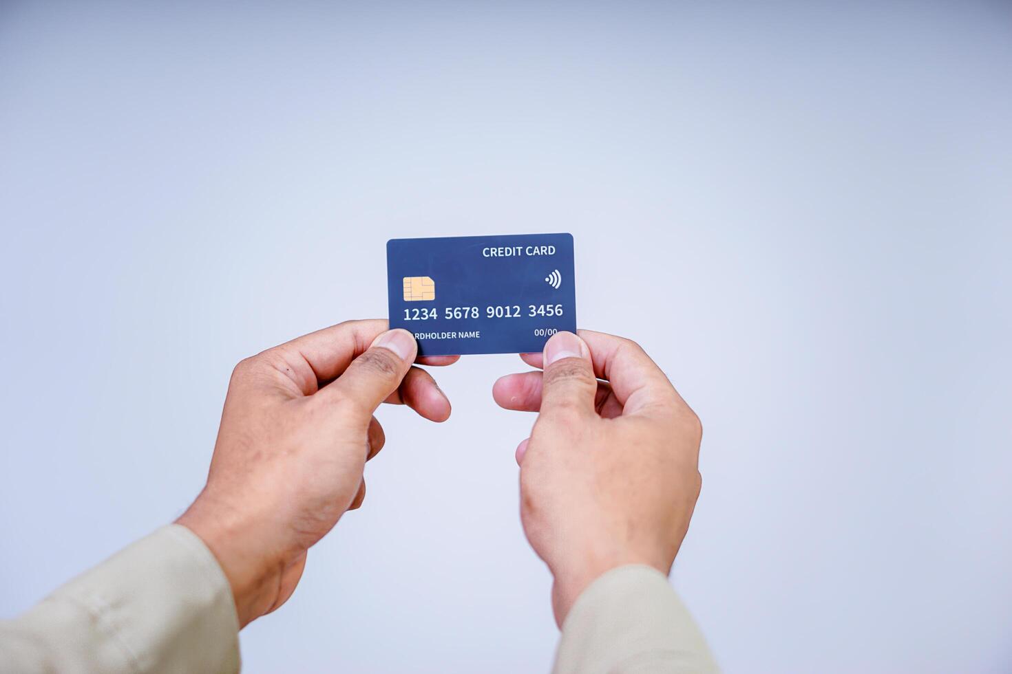 A hand holding a modern credit card with a microchip against a plain background. photo